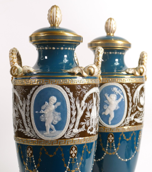 A pair of Minton two handled Pate-sur-Pate vase & covers, gilded and decorated with cupids & scrolling foliage by Harry Hollins